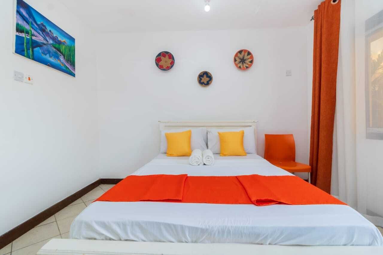 A hotel room with a bed, two pillows, a chair, and a painting on the wall.