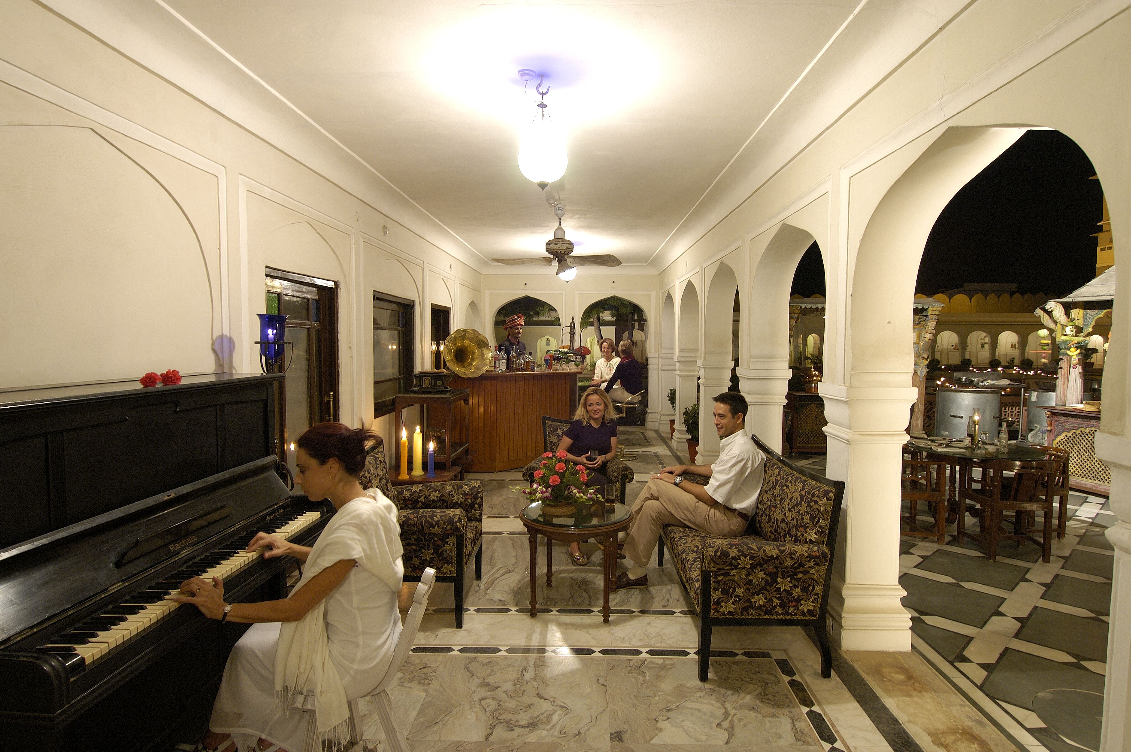 Amplia sala de estar con un piano de cola, asientos cómodos y una fuente decorativa.