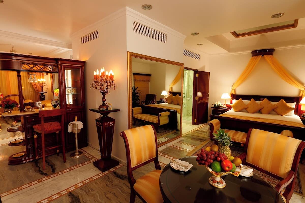 A hotel room with a bed, a dining area, a sitting area, and a bathroom.
