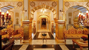 Un interior lujoso con arcos dorados ornamentados, un gran candelabro y muebles suntuosos.