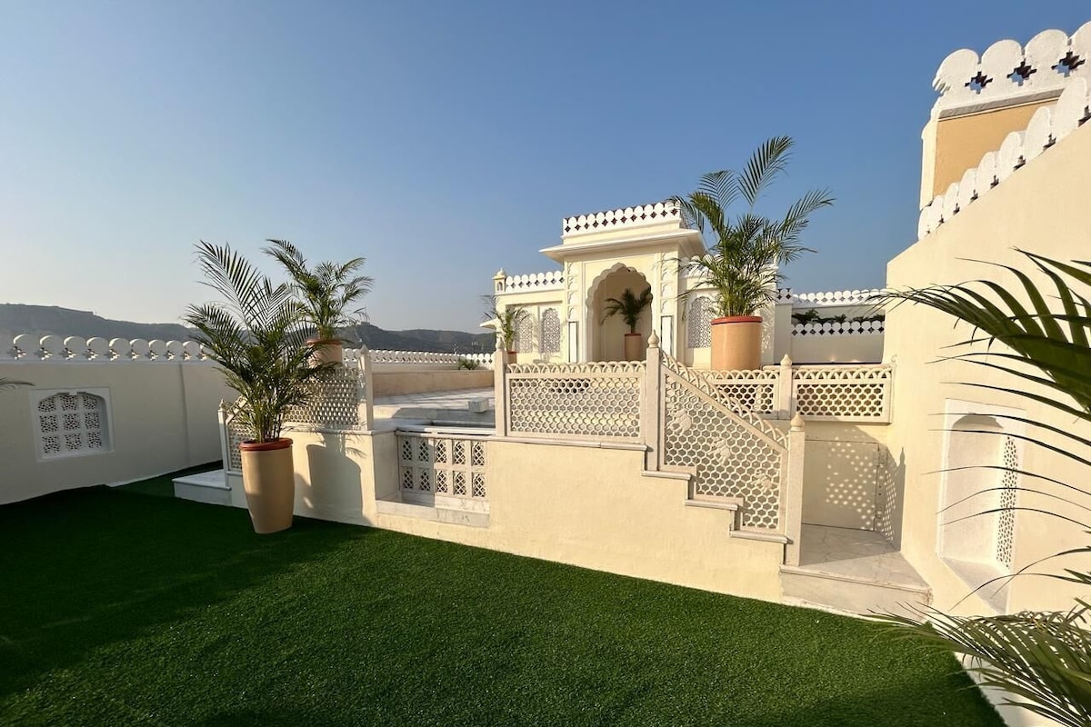A courtyard with artificial green grass, white walls, and decorative arches.