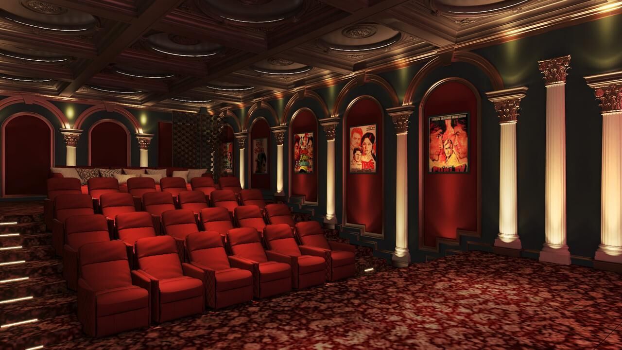 Un teatro con butacas rojas, columnas ornamentales y una alfombra estampada.
