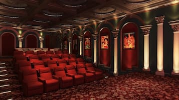 Un teatro con butacas rojas, columnas ornamentales y una alfombra estampada.