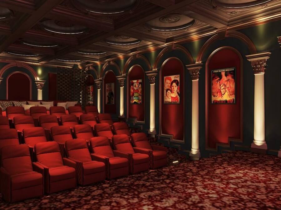 Un teatro con butacas rojas, columnas ornamentales y una alfombra estampada.