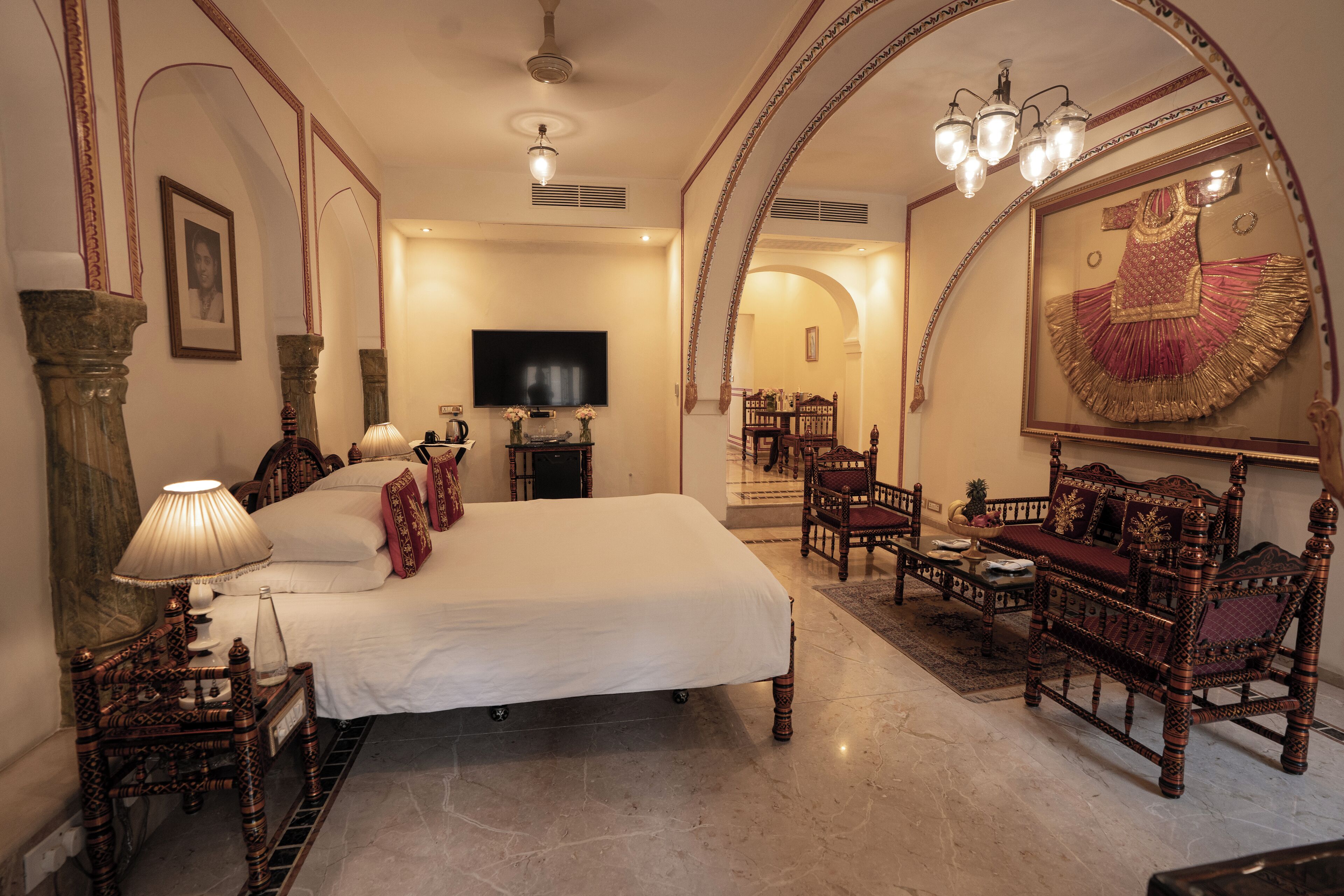 A spacious bedroom with a large bed, a television, and ornate furniture.