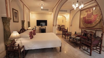 A spacious bedroom with a large bed, a television, and ornate furniture.