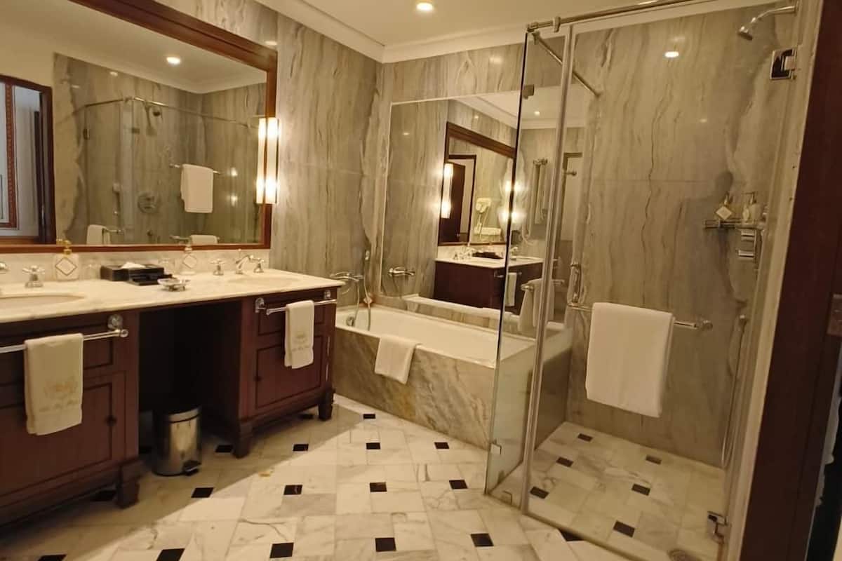 A modern bathroom with a marble floor, a glass-enclosed shower, and a large mirror.