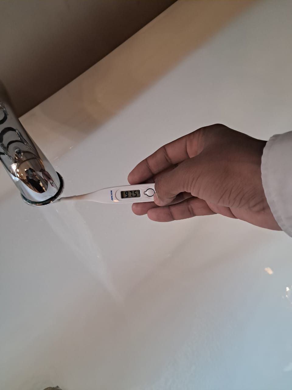 Une main tenant un thermomètre numérique dont l’écran affiche une température de 8,51 degrés.