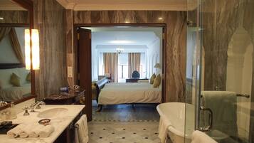 A hotel bathroom with a marble floor, a large mirror, a sink, and a bathtub.