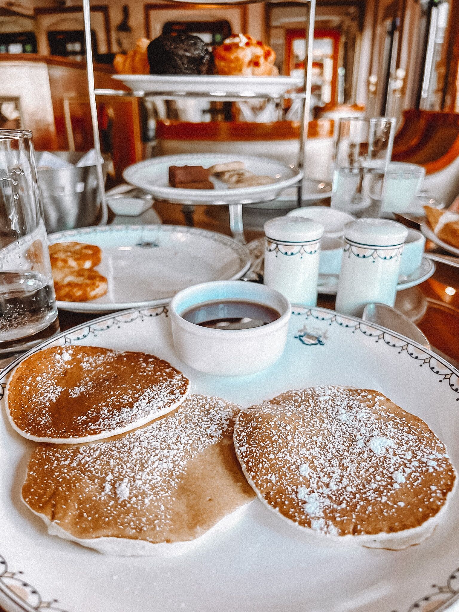 A breakfast setting with pancakes, coffee, and tea.