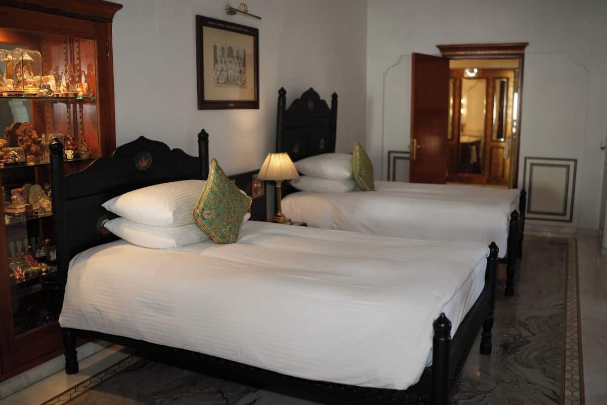 A hotel room with two beds, a wooden headboard, a lamp, and a framed picture on the wall.
