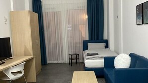 Une chambre d’hôtel comprenant un lit, un bureau, une chaise, un canapé et une petite table.