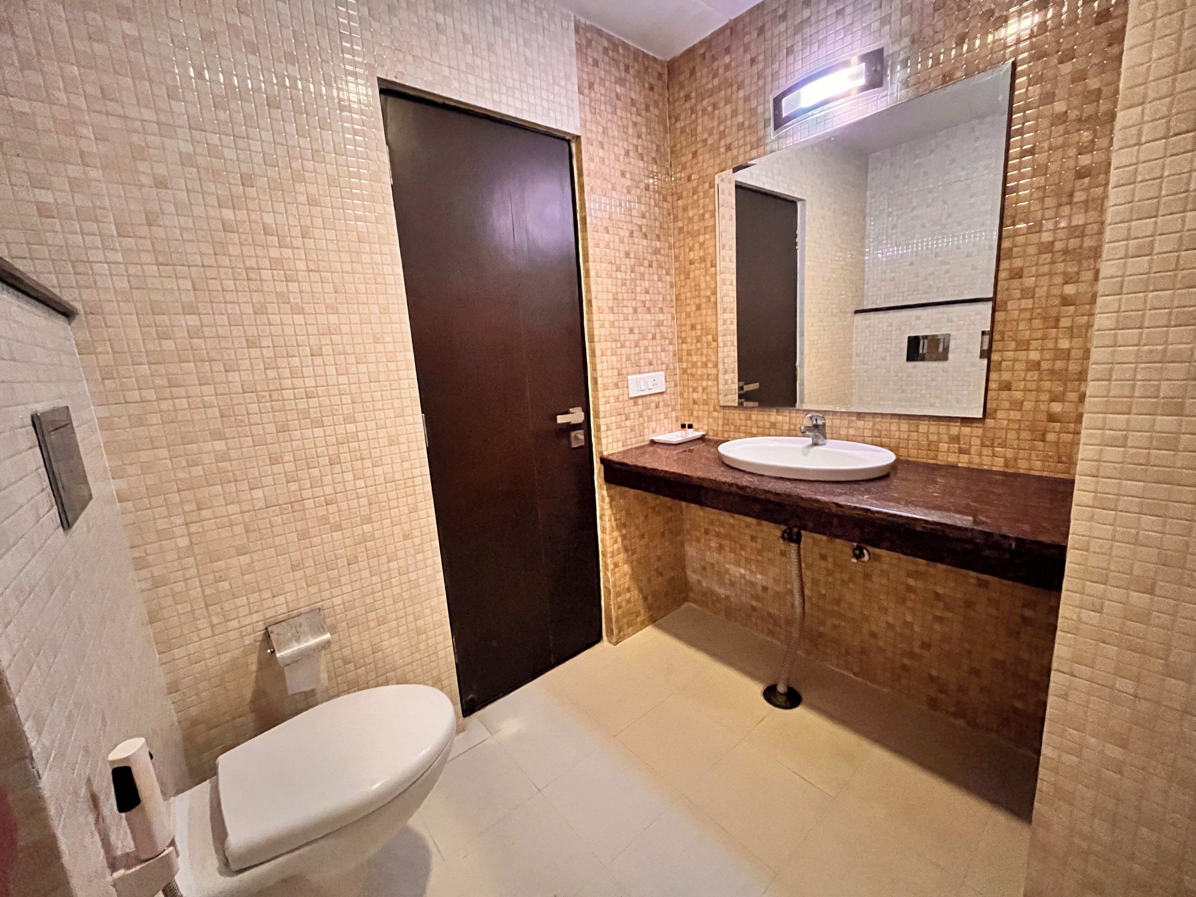A bathroom with a toilet, sink, and mirror.