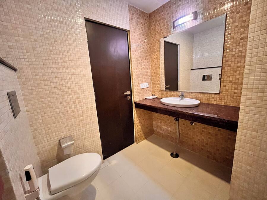 A bathroom with a toilet, sink, and mirror.