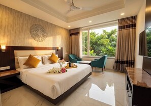 A hotel room with a large bed, a desk, a chair, and a TV. - Hotel The ONIX (Dehradun)