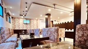 Un salon moderne comprenant un ensemble de canapés, une table basse en verre décorée de galets et un téléviseur à écran plat fixé au mur.