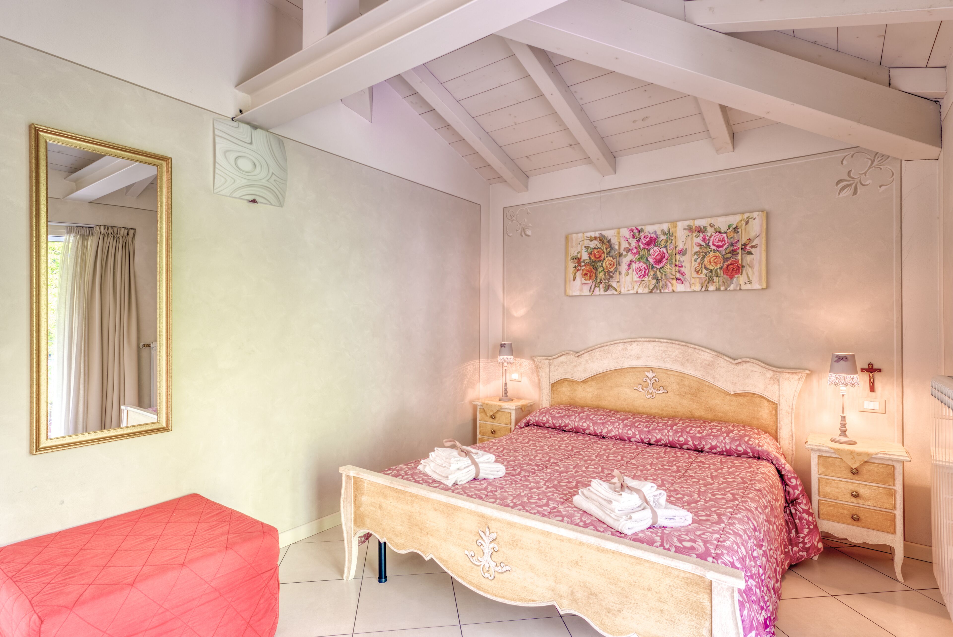 Une chambre à coucher avec un lit, des tables de chevet, un miroir et une chaise rouge.