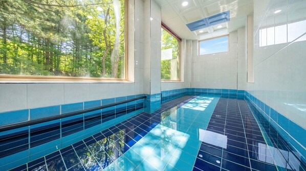 Una piscina con azulejos azules y ventanas amplias.
