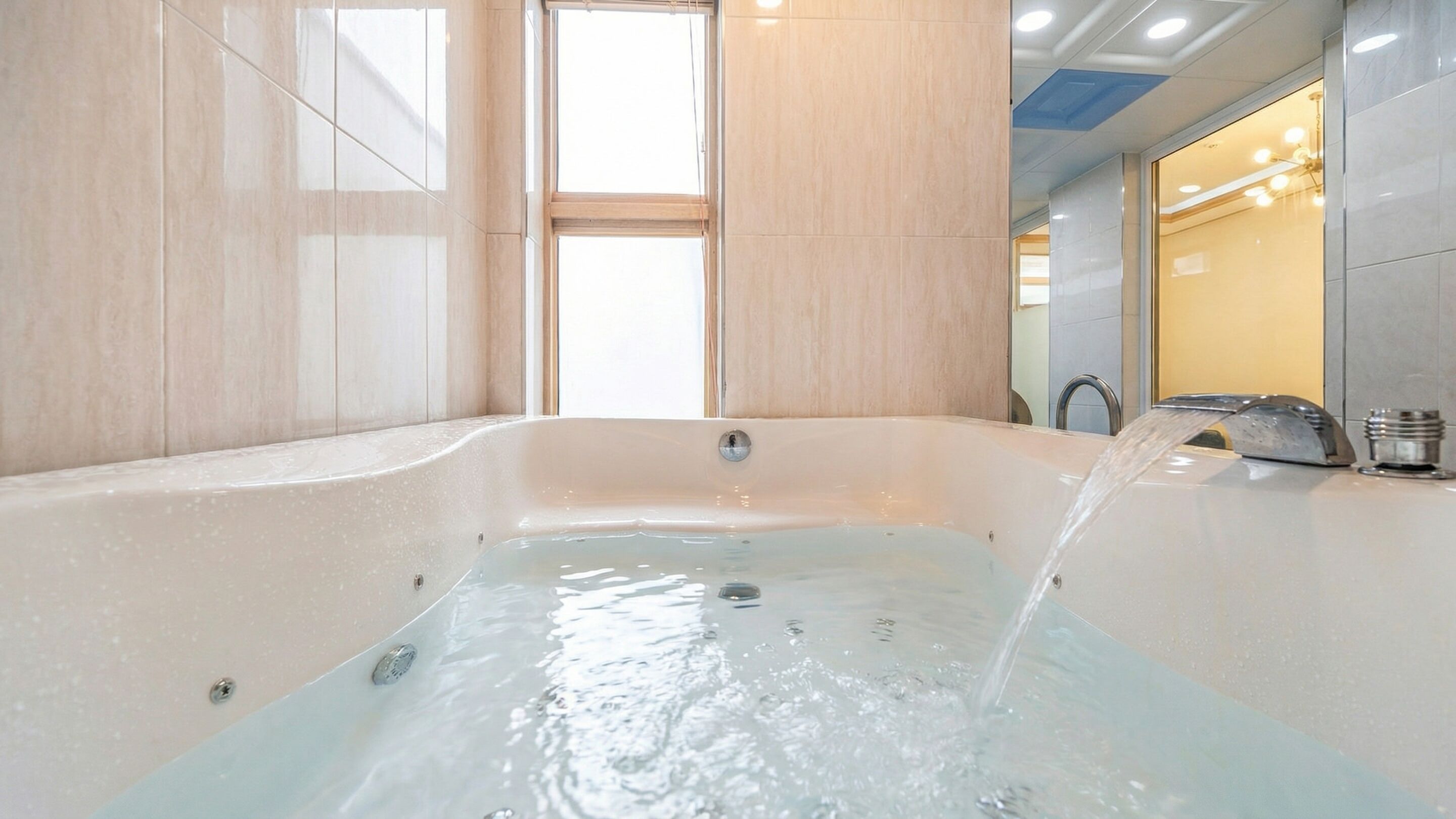Un baño moderno con una bañera grande, un grifo a la vista y un espejo que refleja el interior.
