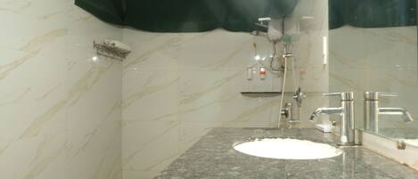 A bathroom with a marble sink, a mirror, and a shower.
