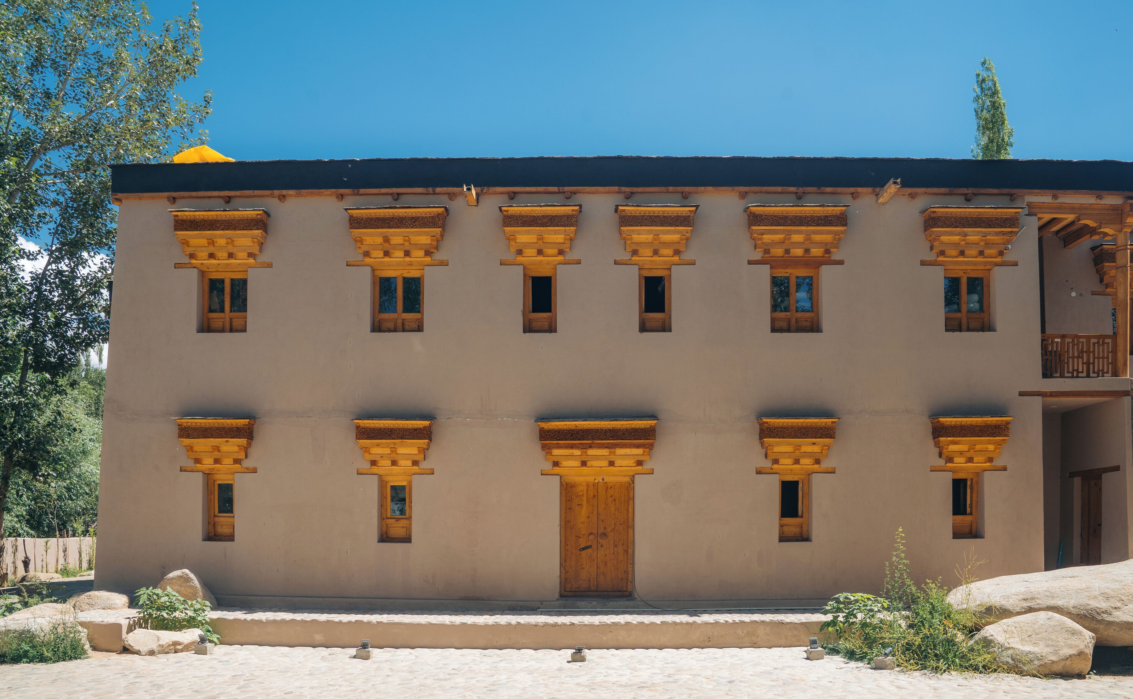 A building with a symmetrical facade, multiple windows with wooden frames, and a central door.