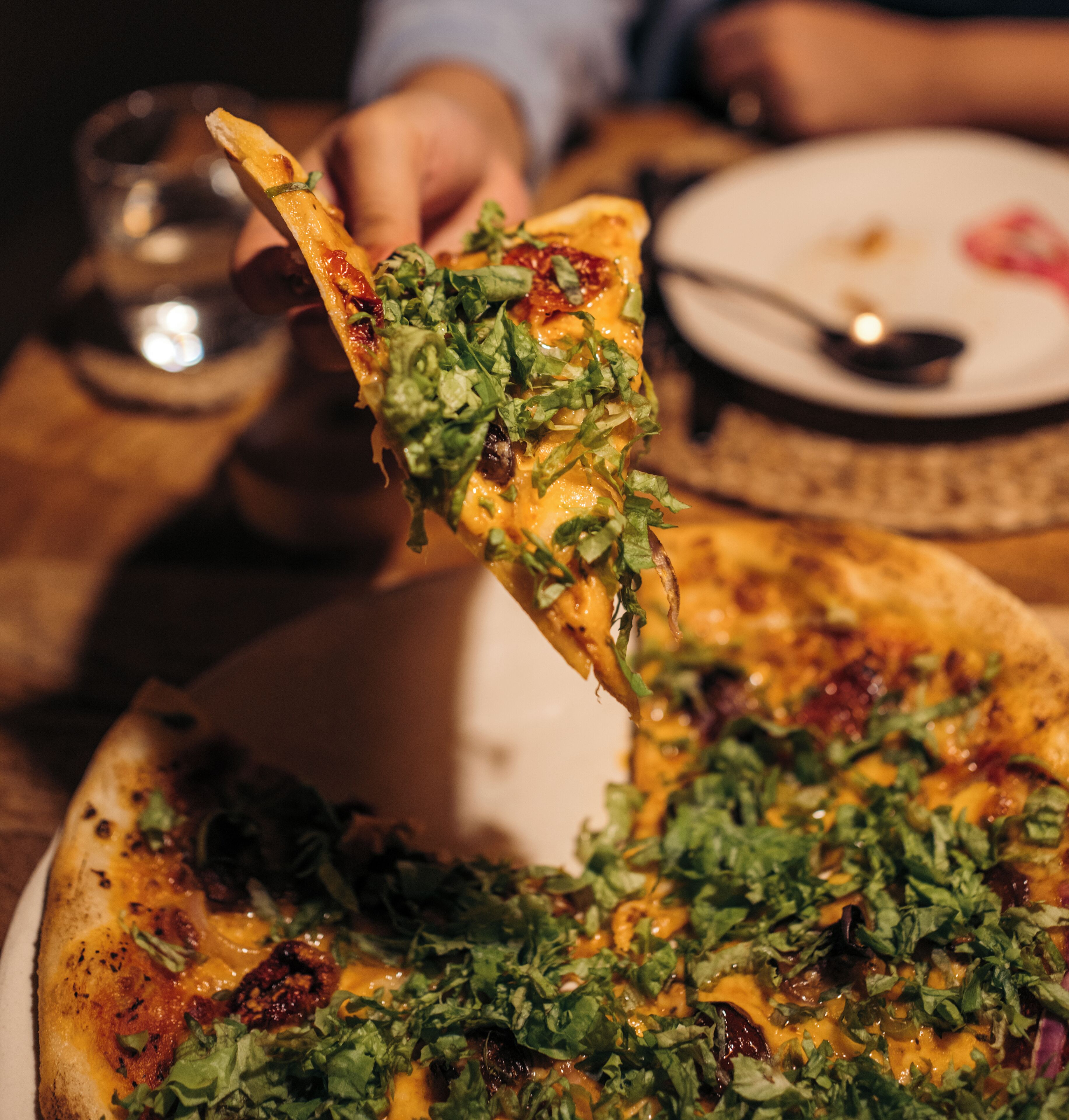 Pizza con ingredientes siendo levantada.