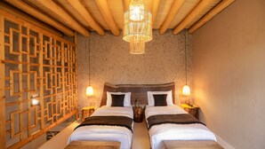 Ein Zimmer mit zwei Betten, einem Holzkopfteil, einer dekorativen Wandverkleidung und einer Pendelleuchte.