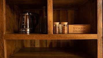 A wooden shelf with a coffee maker, a glass bottle, and jars labeled 'DOLKHAR'.