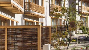 Ein modernes Gebäude mit Holzbalkonen und einem Gartenbereich mit Steinen und Pflanzen.