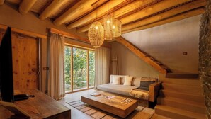 Ein gemütliches Wohnzimmer mit Couch, Holz-Couchtisch und einer Treppe, die zu einer oberen Etage führt.
