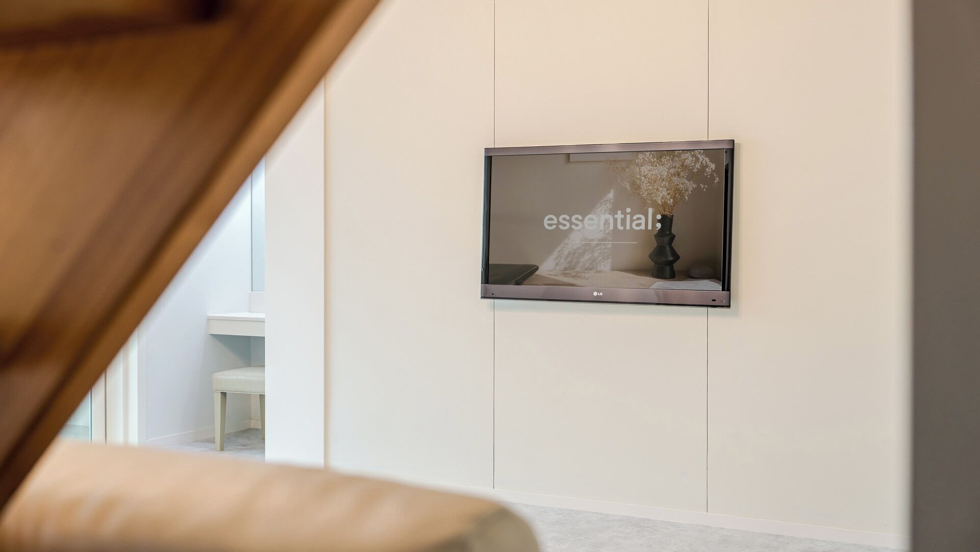 Een moderne kamer met een wandgemonteerde flatscreen-tv waarop het woord 'essential:' staat.