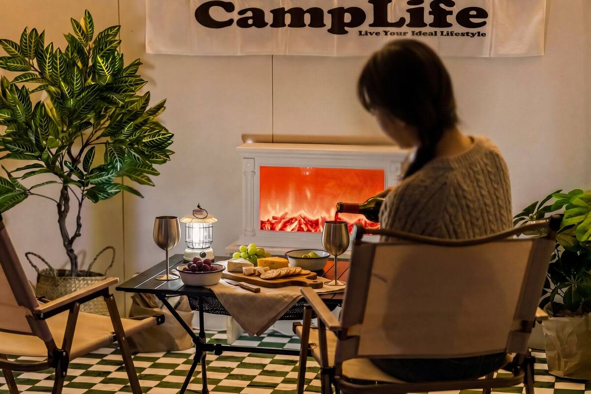 Ein gemütliches Interieur mit Kamin, Tisch mit Speisen und Getränken sowie einer dort sitzenden Person.