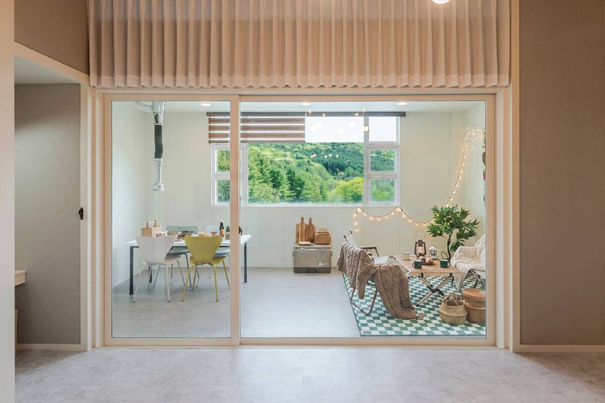Ein modernes Interieur mit Essbereich, Blick ins Grüne und einer gemütlichen Sitzgelegenheit mit kariertem Boden.
