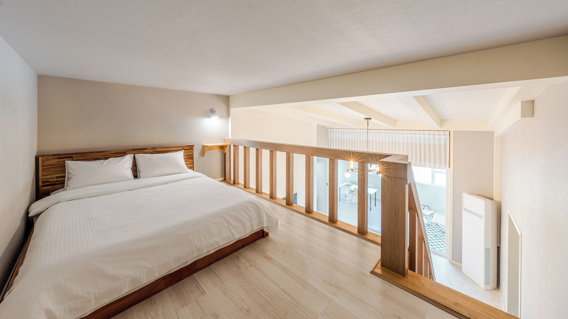 Un dormitorio con cama de madera, un balcón con barandilla y vistas al exterior.