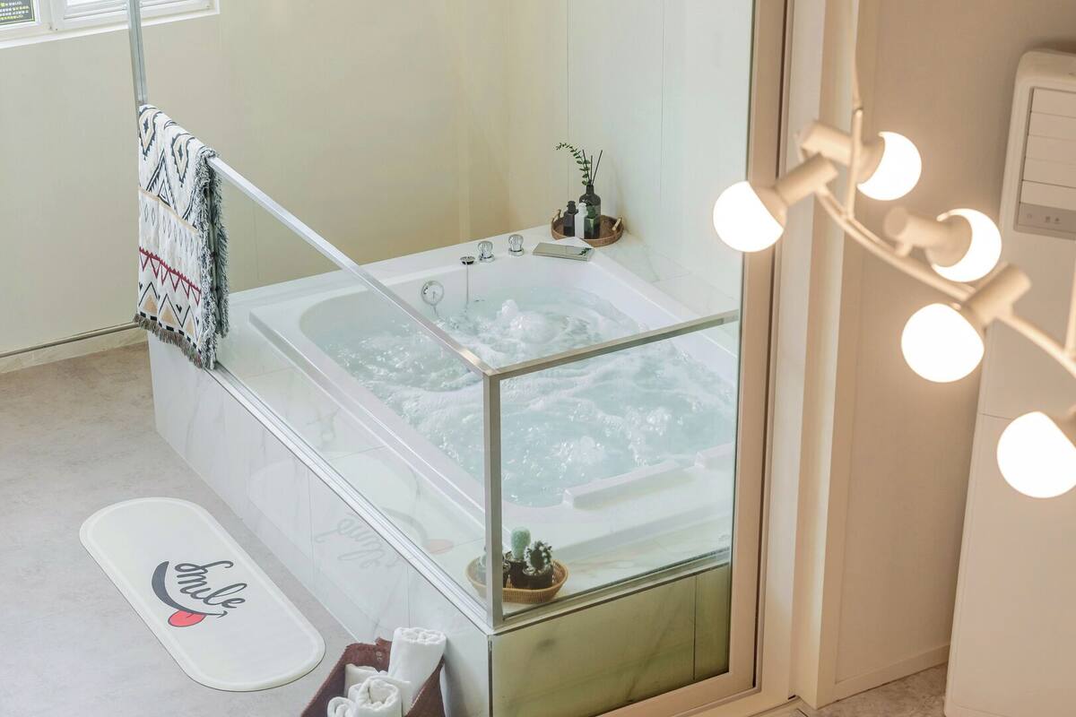 Ein Badezimmer mit Badewanne, Dusche, einem Waschtisch mit Glasabtrennung und einem Handtuchhalter.