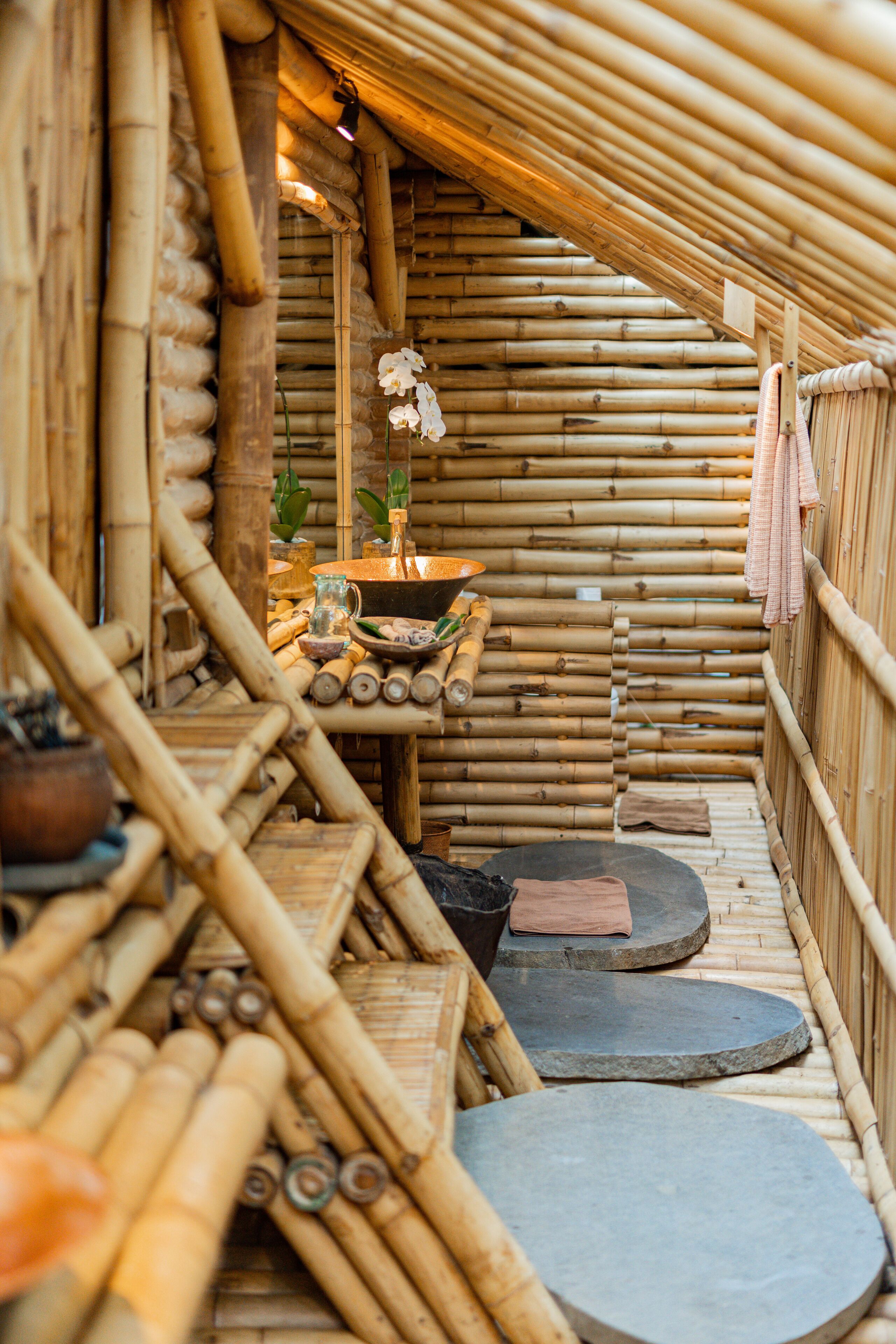 A bamboo structure with a small table, a shelf with items, and a hanging cloth.