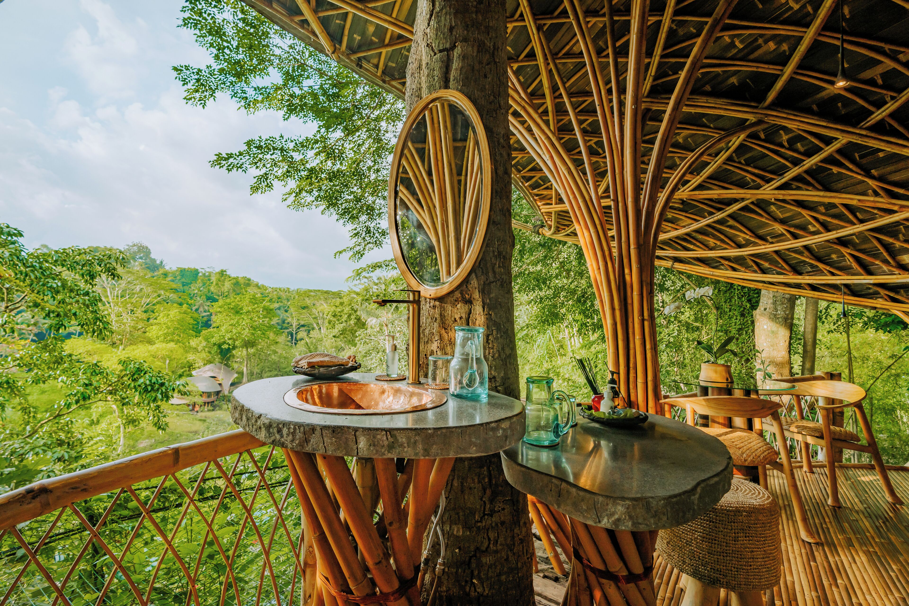 A bamboo structure with a round table and a mirror, surrounded by lush greenery and a scenic view.