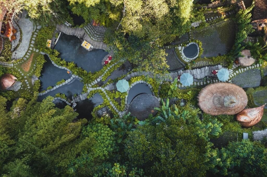 An aerial view of a garden with multiple circular ponds, stone pathways, and lush greenery.