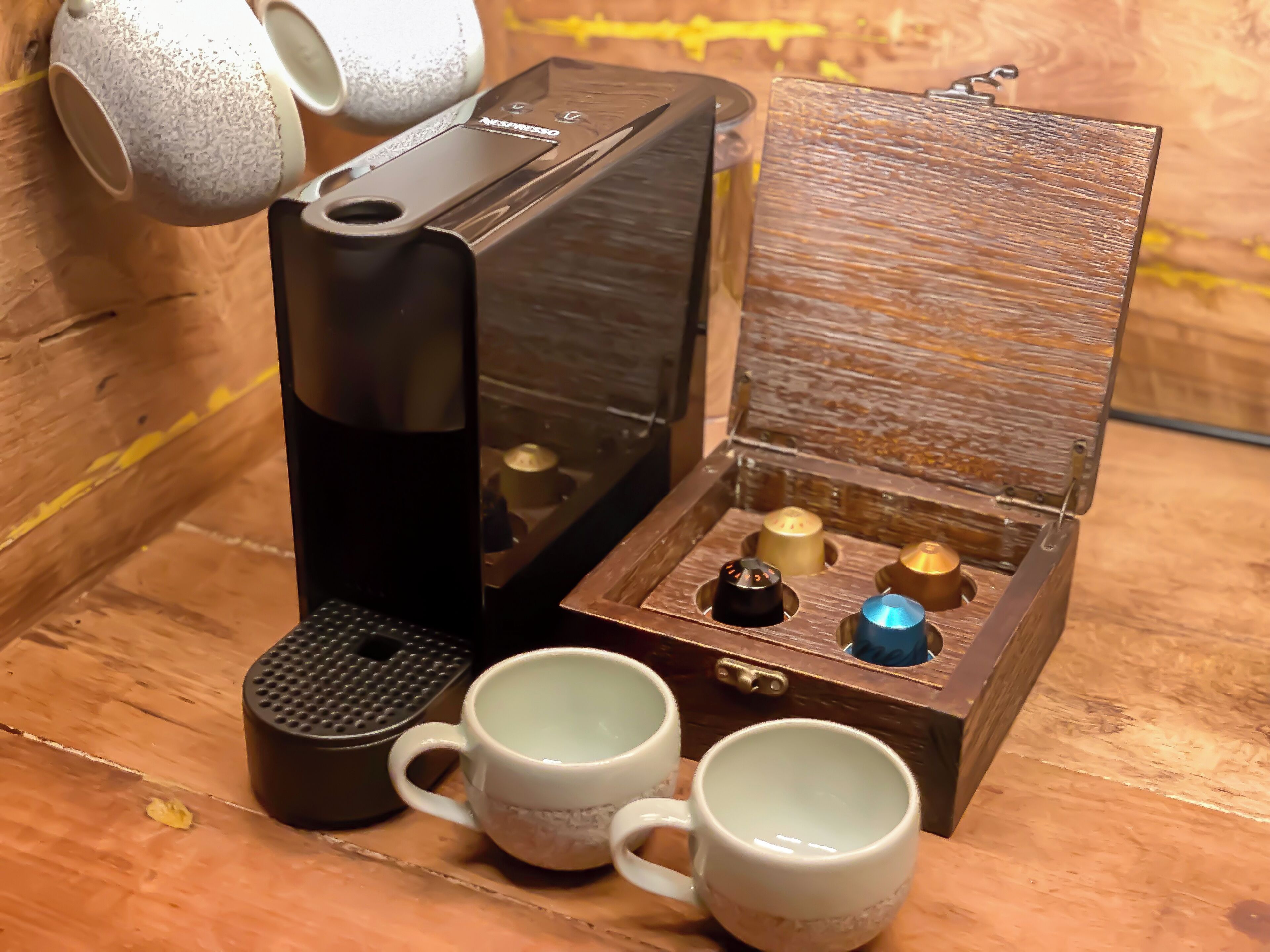 A coffee maker with a wooden box containing three cups and a small container.
