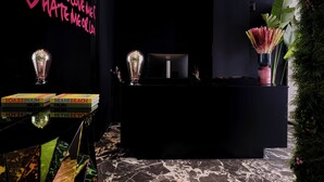 A reception area with a black counter, a neon sign, and a decorative plant. - Nur Outline Aparthotel (Athens)