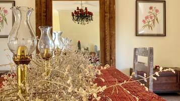 Una habitación con un largo y rojo suelo estampado, un marco de puerta de madera, una araña y una cabeza de animal montada.