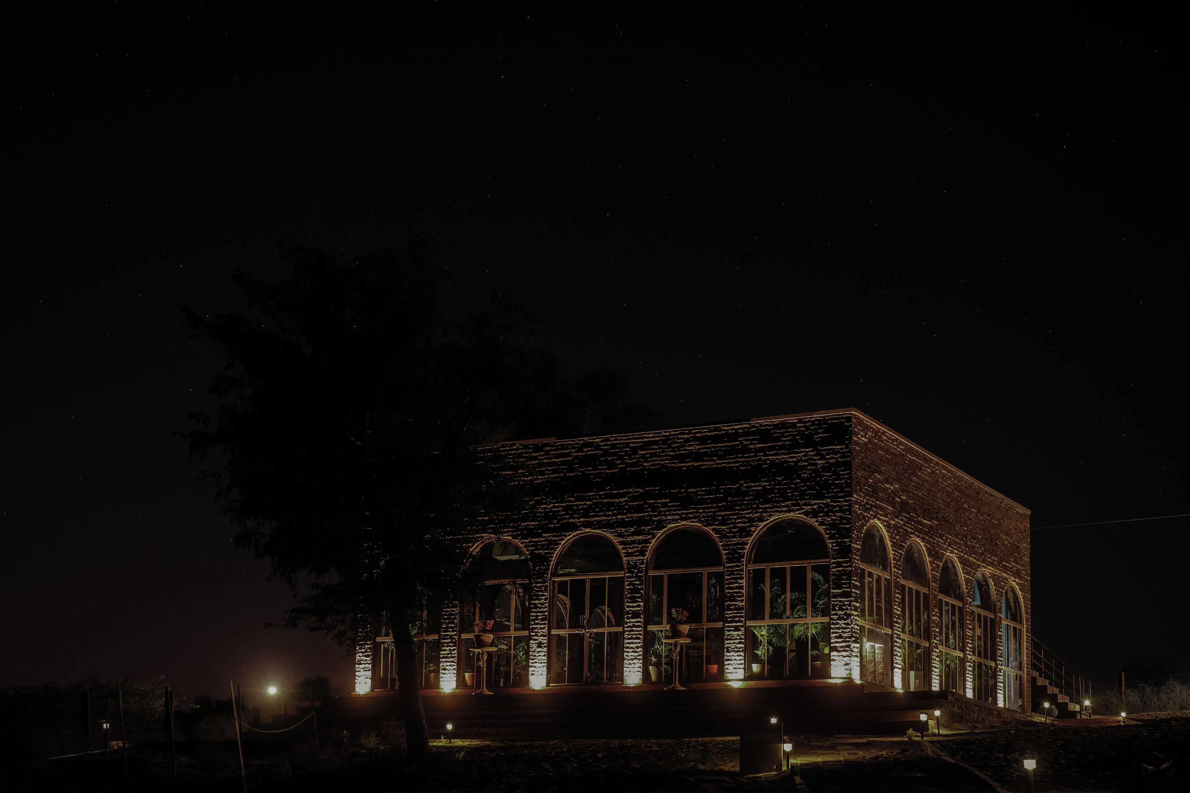 A building with a brick facade and arched windows, illuminated at night.