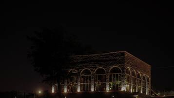 A building with a brick facade and arched windows, illuminated at night.