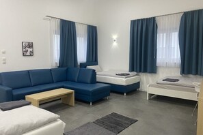 A modern, well-lit living room with a blue sofa, a white bed, and a small table. - Fabella Flats Forchheim - Fabella 89 (Forchheim)
