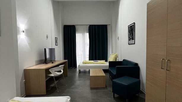 A compact hotel room with a bed, a desk with a chair, a sofa, and a wardrobe. - Fabella Flats Forchheim - 20 (Forchheim)