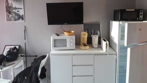 A compact kitchenette with a microwave, toaster, and a small fridge. A television is mounted above the counter. - Studio Balaruc LES Bains Proche Cure ET Plage (Balaruc-les-Bains)