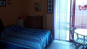 A bedroom with a bed, a dresser, a window with a view, and a table with chairs. - Studio Balaruc LES Bains Proche Cure ET Plage (Balaruc-les-Bains)