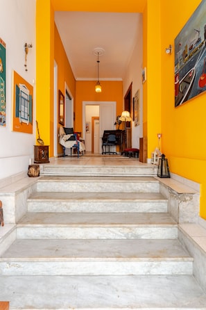 A staircase leading to a living area with a piano, a lamp, and a painting on the wall. - Acropolis Masterpiece Neoclassical Mansion (Athina)