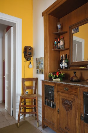 A wooden cabinet with a mirror, a chair, and a shelf with bottles. - Acropolis Masterpiece Neoclassical  Mansion (Athina)