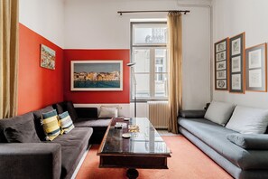 A living room with a red accent wall, a large window with curtains, a sofa, a coffee table, and framed artwork on the wall. - Acropolis Masterpiece Neoclassical Mansion (Athina)